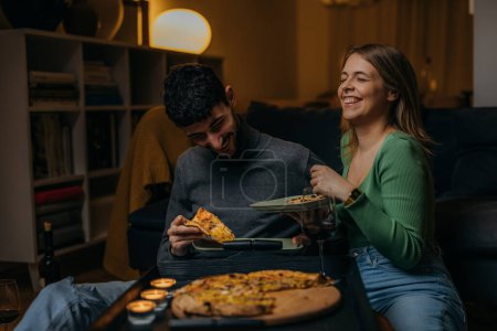 Foto de Feliz pareja comiendo pizza en casa - Imagen libre de derechos