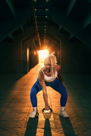 Téléchargez les photos : A blonde woman is lifting a weight - en image libre de droit