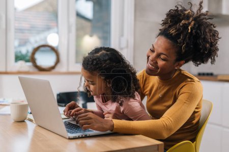 Photo for Mother and daughter type together on the laptop - Royalty Free Image