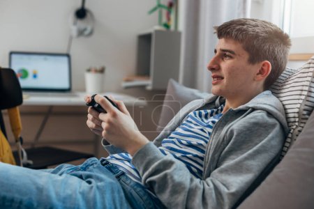 Téléchargez les photos : Side view of a teenage boy playing video games - en image libre de droit