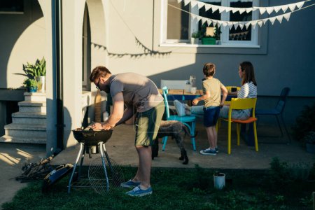 Photo for Father is setting up a grill in the backyard - Royalty Free Image