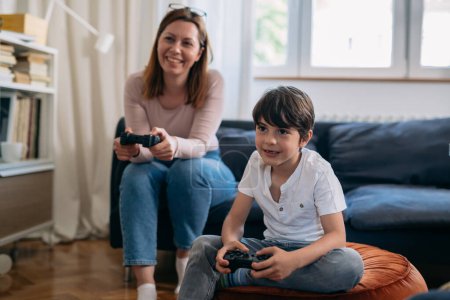 Téléchargez les photos : Mère et fils jouer à des jeux vidéo à la maison - en image libre de droit