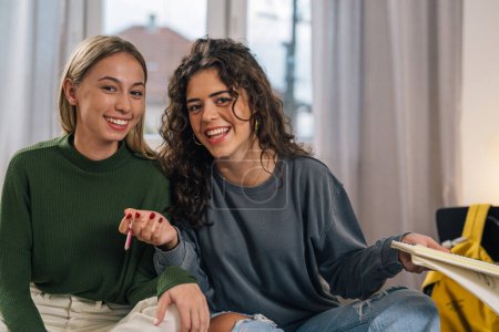 Téléchargez les photos : Vue de face de deux étudiants heureux qui étudient ensemble à la maison - en image libre de droit