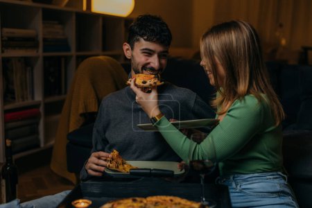 Photo for Woman feeding her boyfriend with pizza - Royalty Free Image