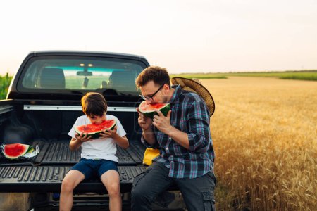 Téléchargez les photos : Father and son are enjoying a sweet watermelon o a hot day - en image libre de droit