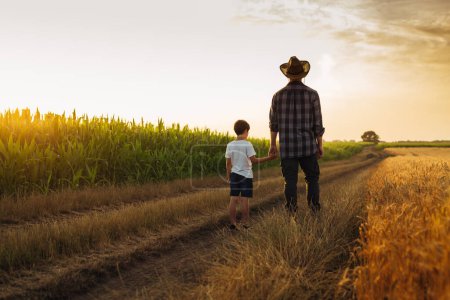 Photo for Father and son holding hands and walking on the country road - Royalty Free Image