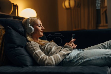 Téléchargez les photos : Jolie femme caucasienne se relaxe sur le canapé - en image libre de droit