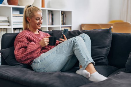 Téléchargez les photos : Young blonde woman relaxes on the sofa at home - en image libre de droit