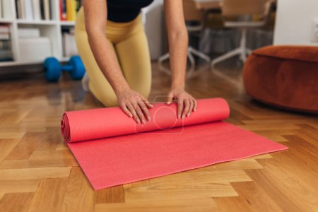 Téléchargez les photos : Womans hands are unrolling the yoga mat for exercising - en image libre de droit