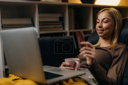 Téléchargez les photos : Young Caucasian woman is using her credit card for online payment - en image libre de droit