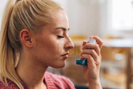 Téléchargez les photos : Close up view of a blonde woman with an asthma inhaler - en image libre de droit