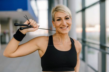 Photo for Middle aged sportswoman with a jump rope looks at the camera - Royalty Free Image