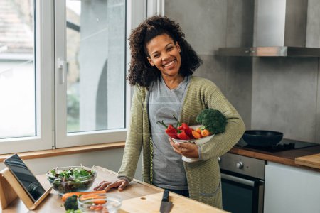 Téléchargez les photos : Happy mixed race woman is holding a bowl full of vegetables - en image libre de droit