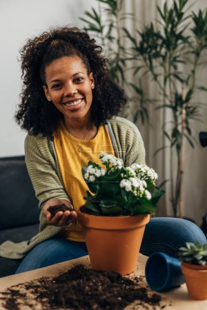 Foto de Mujer sonriente está mirando a la cámara mientras planta la flor - Imagen libre de derechos