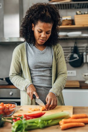 Photo for Mixed race woman is chopping carrots - Royalty Free Image