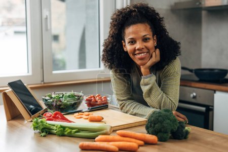 Téléchargez les photos : Happy mixed race woman is in the kitchen and looks at the camera - en image libre de droit