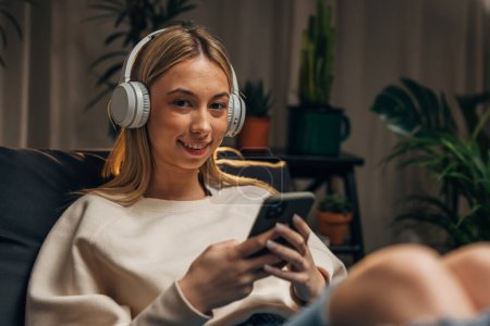 Photo for Young woman with headphones is looking at the camera - Royalty Free Image