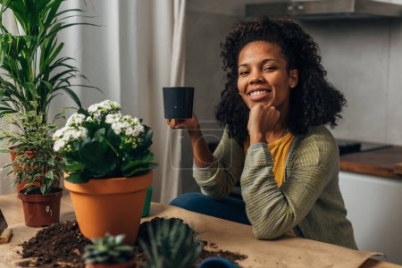 Téléchargez les photos : Une femme est satisfaite après avoir replanté ses plantes d'intérieur - en image libre de droit