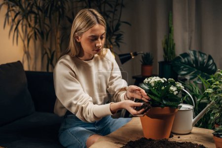 Photo for A blonde woman fills up the flowerpot with dirt - Royalty Free Image