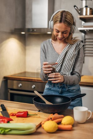 Photo for Happy blonde woman spices the food before cooking - Royalty Free Image
