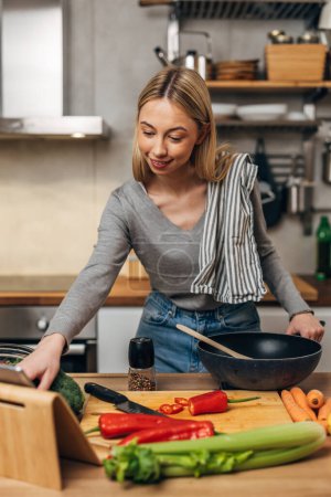 Photo for Front view of a young blonde woman cooking in the kitchen - Royalty Free Image
