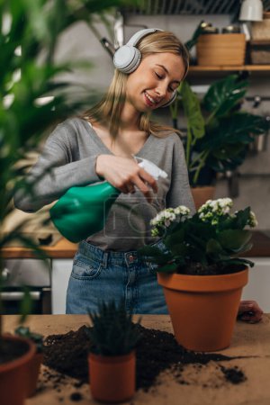Téléchargez les photos : Une jeune femme se douche d'une plante d'intérieur - en image libre de droit