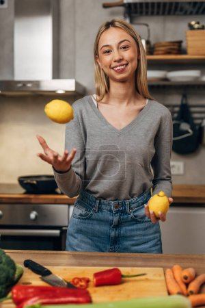 Téléchargez les photos : Jeune femme blonde tenant des citrons dans la cuisine - en image libre de droit