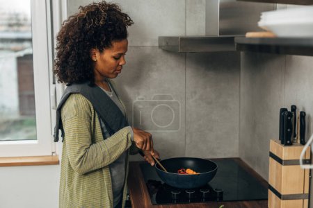 Téléchargez les photos : Une femme cuisine sur la cuisinière - en image libre de droit