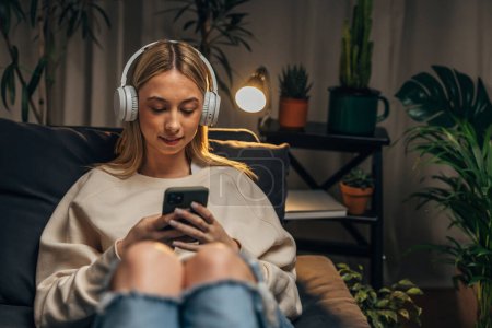 Téléchargez les photos : Une femme blonde passe la soirée seule dans son appartement décoré de plantes - en image libre de droit