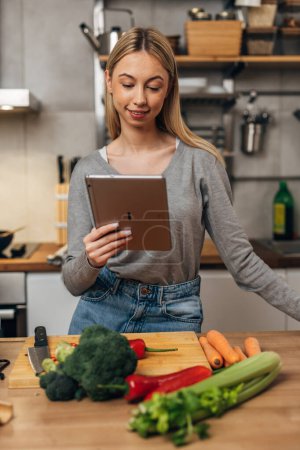 Photo for A young woman reads a recipe on tablet - Royalty Free Image