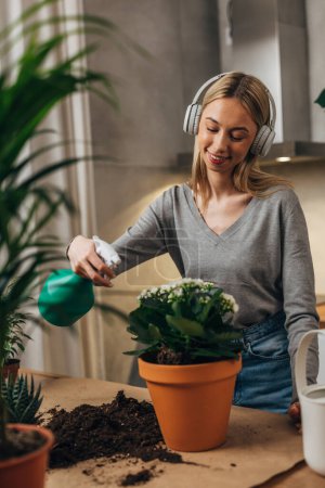 Téléchargez les photos : Heureuse jeune femme prend soin de ses plantes d'intérieur - en image libre de droit