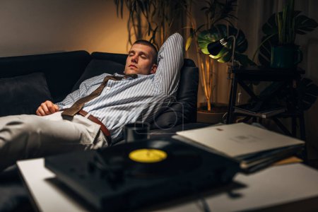 Photo for A young businessman enjoys listening to records after a hard day at work - Royalty Free Image