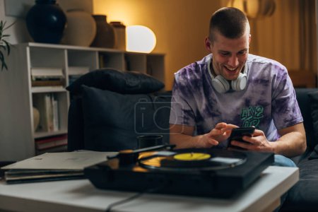 Photo for A happy handsome man is chatting with his friends while listening to music played on gramophone - Royalty Free Image