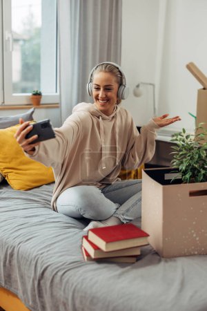 Photo for A female college student enjoying her new living space. She is having a video call. - Royalty Free Image