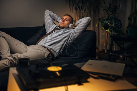Photo for A young businessman is resting at home with music after a hard day at work - Royalty Free Image