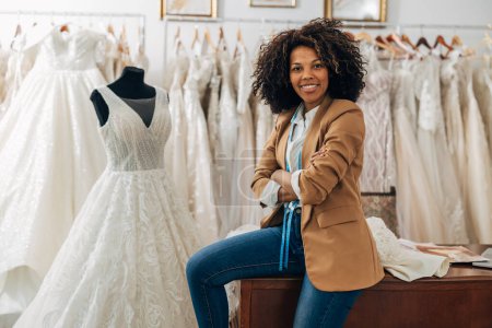 Téléchargez les photos : Une femme heureuse travaille dans un magasin de mariage comme tailleur - en image libre de droit