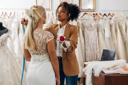 Téléchargez les photos : Un designer fixe une robe de mariée pour une mariée à être. - en image libre de droit