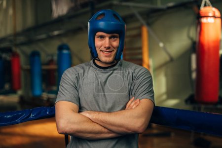 Photo for A Caucasian boxer is standing in the ring with a helmet for protection - Royalty Free Image