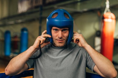 Photo for Closeup portrait of a boxer putting on a head protection before a match. - Royalty Free Image