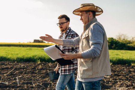 Téléchargez les photos : Un agriculteur et un inspecteur traversent le champ. - en image libre de droit