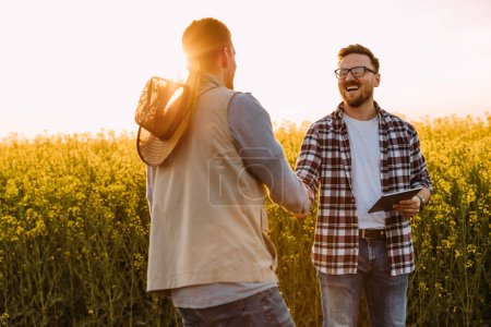 Photo for Two farmers greet each other in the field - Royalty Free Image