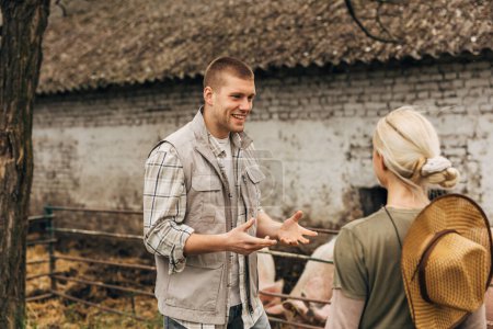 Foto de Un hombre caucásico habla con entusiasmo a una mujer rubia en la granja. - Imagen libre de derechos