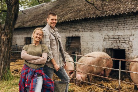 Foto de Esposo y esposa de pie en su granja de animales sonriendo. - Imagen libre de derechos