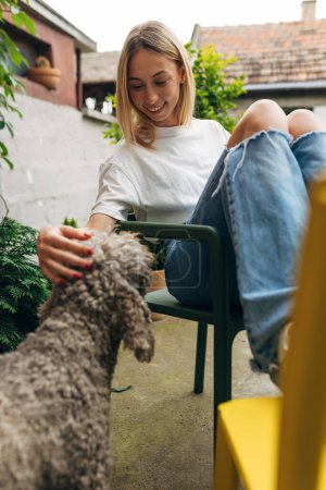 Photo for A beautiful blond woman pats a dog in the garden. - Royalty Free Image