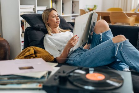 Photo for A woman looks at her collection of vinyl records. - Royalty Free Image