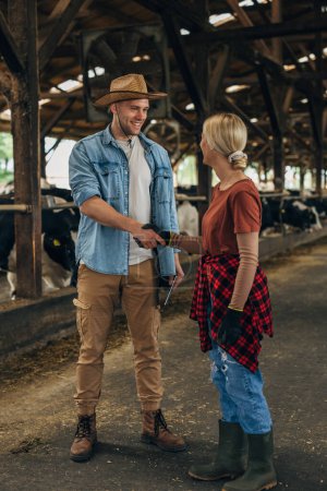 Photo for A man with a leghorn shakes hands with a woman working in a stable. - Royalty Free Image