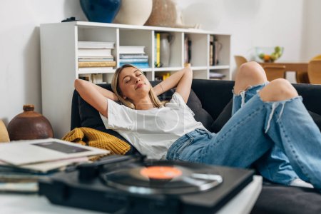 Photo for Caucasian woman relaxing with music from gramophone at home - Royalty Free Image