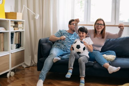 Photo for Caucasian family watching a soccer game together and cheering. - Royalty Free Image