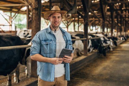 Photo for Portrait of a farmer holding a tablet in a barn. - Royalty Free Image