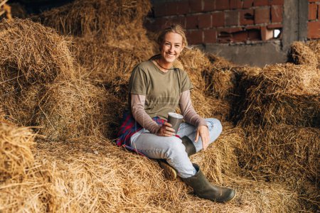 Foto de Retrato de una hermosa granjera feliz sentada en una pila de heno. - Imagen libre de derechos